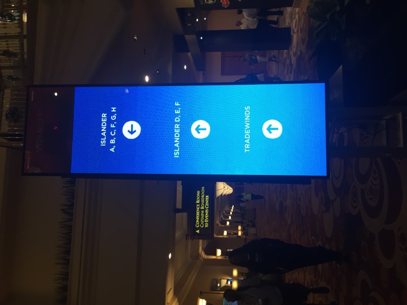 Digital wayfinding tower in a VMworld conference corridor directing attendees to the Islander and Tradewinds rooms.