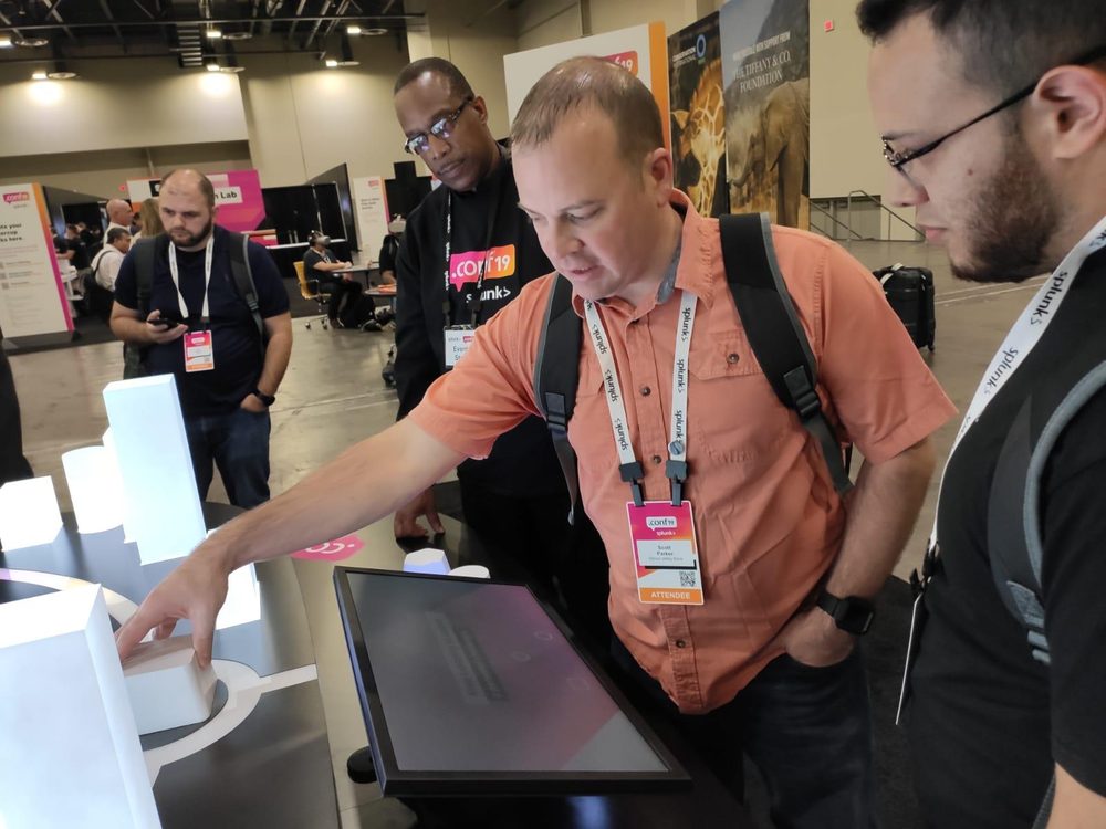 An attendee interacting with a lit zone of the smart-city model at the Splunk booth